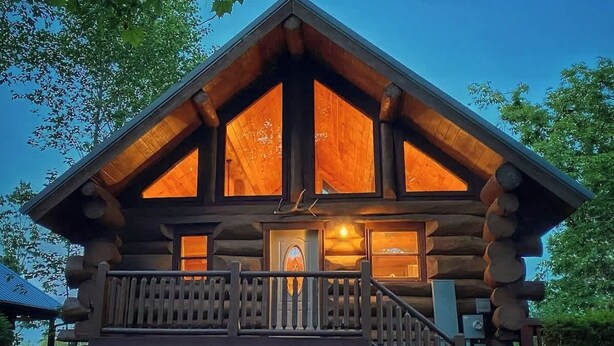 A log cabin with a balcony and a staircase leading to the entrance.