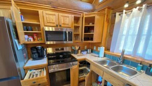 A compact kitchen with wooden cabinets, a microwave, stove, oven, and a sink.