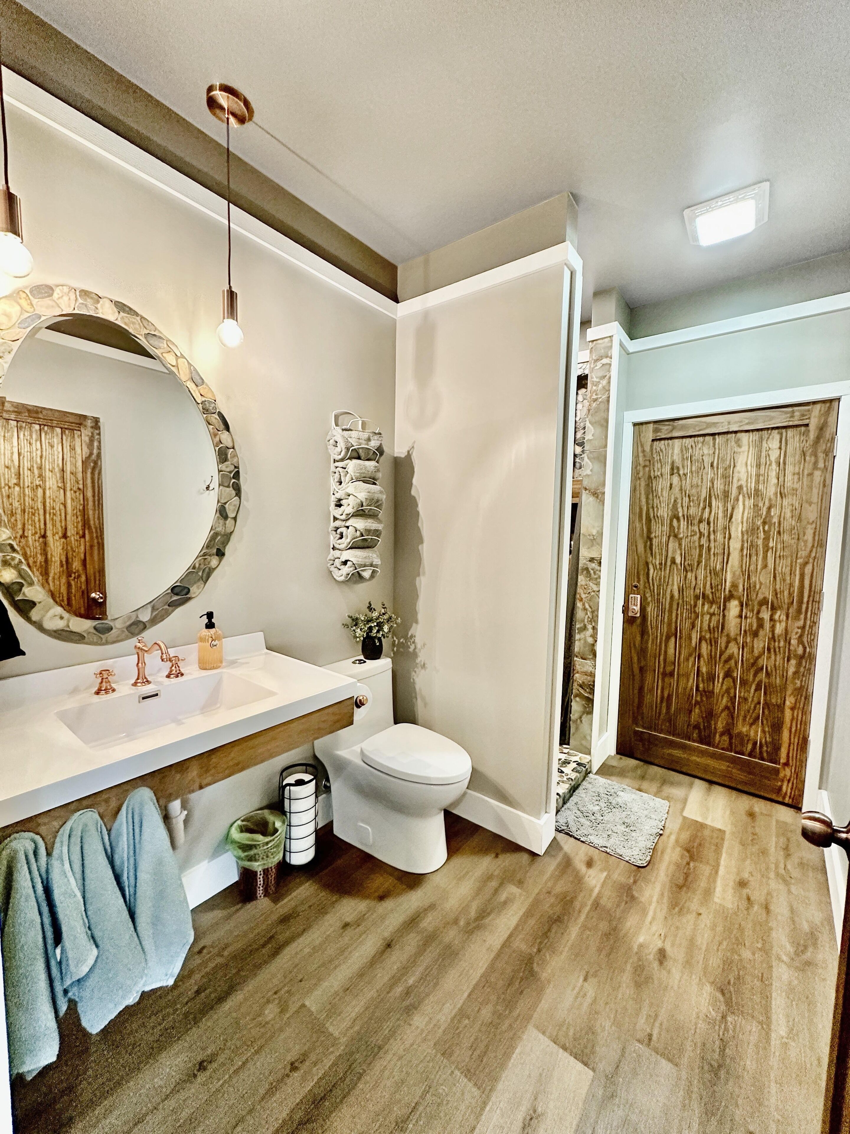 A bathroom with a white sink, a mirror with a stone frame, a toilet, and a shower area.