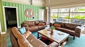 Un salón amplio con sofás de cuero, una mesa de centro de madera y un ventanal con vistas al exterior.