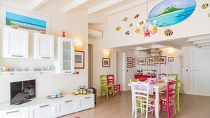 A dining area with colorful chairs, a chandelier, and a view of the sea through a window. - 2 bedroom nice apartment in Donnalucata (Donnalucata)