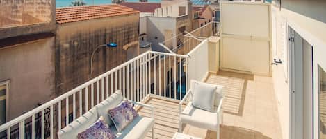Un balcone con arredi bianchi, un tavolo con decorazioni e vista sul mare.