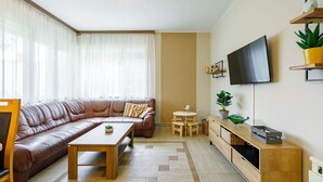 A modern living room with a leather sofa, a wooden coffee table, a small round table, and a TV mounted on the wall. - Stunning private villa for 12 people with WIFI, A/C, TV, patio and pets allowed (Balatonboglár)