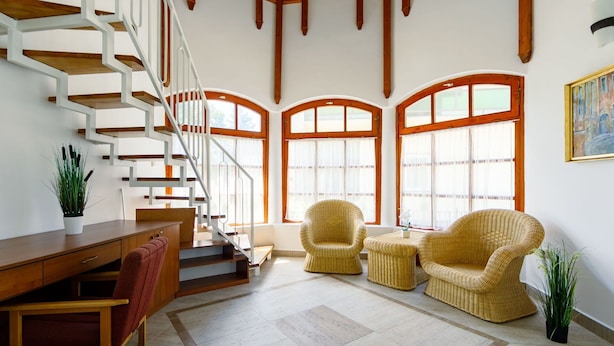 A spacious living area with a wooden staircase, wicker furniture, and large windows. - Stunning private villa for 12 people with WIFI, A/C, TV, patio and pets allowed (Balatonboglár)