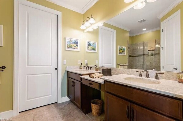 Une salle de bain avec deux lavabos, une douche et un grand miroir.