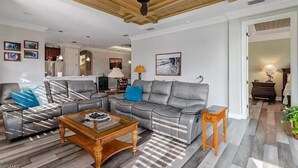 A spacious living room with a ceiling fan, grey leather sofas, a wooden coffee table, and a rug. - Welcome to this Endearing Naples Home! (Naples)