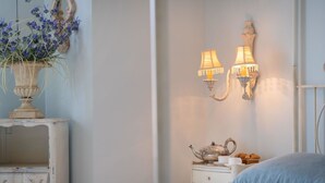 A bedroom with a bed, a nightstand with a teapot, a lamp, and a vase with flowers. - Lovely apartment for 4 guests with WIFI, TV and balcony (Riva Ligure)