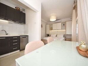 Enjoy meals in this kitchen and dining area, featuring a stainless steel dishwasher and a white table.