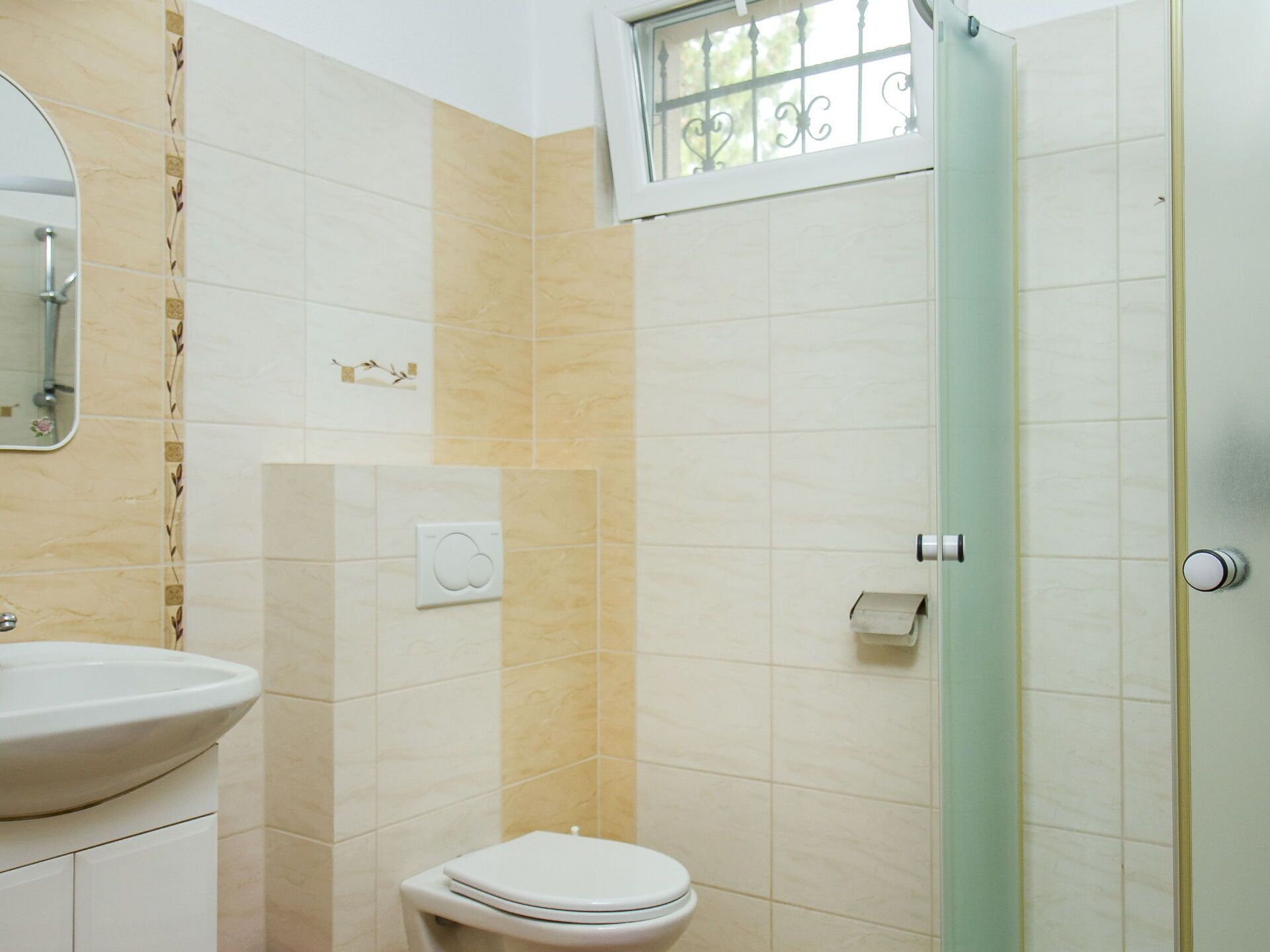 Une salle de bain équipée de toilettes, d’un lavabo et d’une fenêtre avec des barreaux.