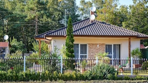 A two-story house with a tiled roof, satellite dishes, and a fenced yard.