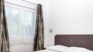 A room with a single bed, a window with sheer curtains, and a wall-mounted light fixture. - Wonderful private villa for 8 guests with terrace and pets allowed (Keszthely)