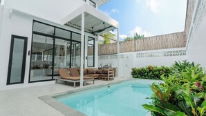 Ein moderner Poolbereich im Freien mit einer verglasten Terrasse, einem Holzdeck und einem integrierten Grill.