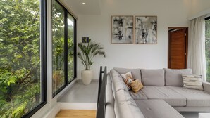 Ein modernes Wohnzimmer mit grauem Sofa, einer Topfpflanze und abstrakter Kunst an der Wand.