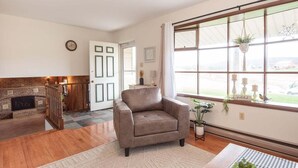 Una sala de estar con chimenea, un ventanal con vistas y un sillón cómodo.