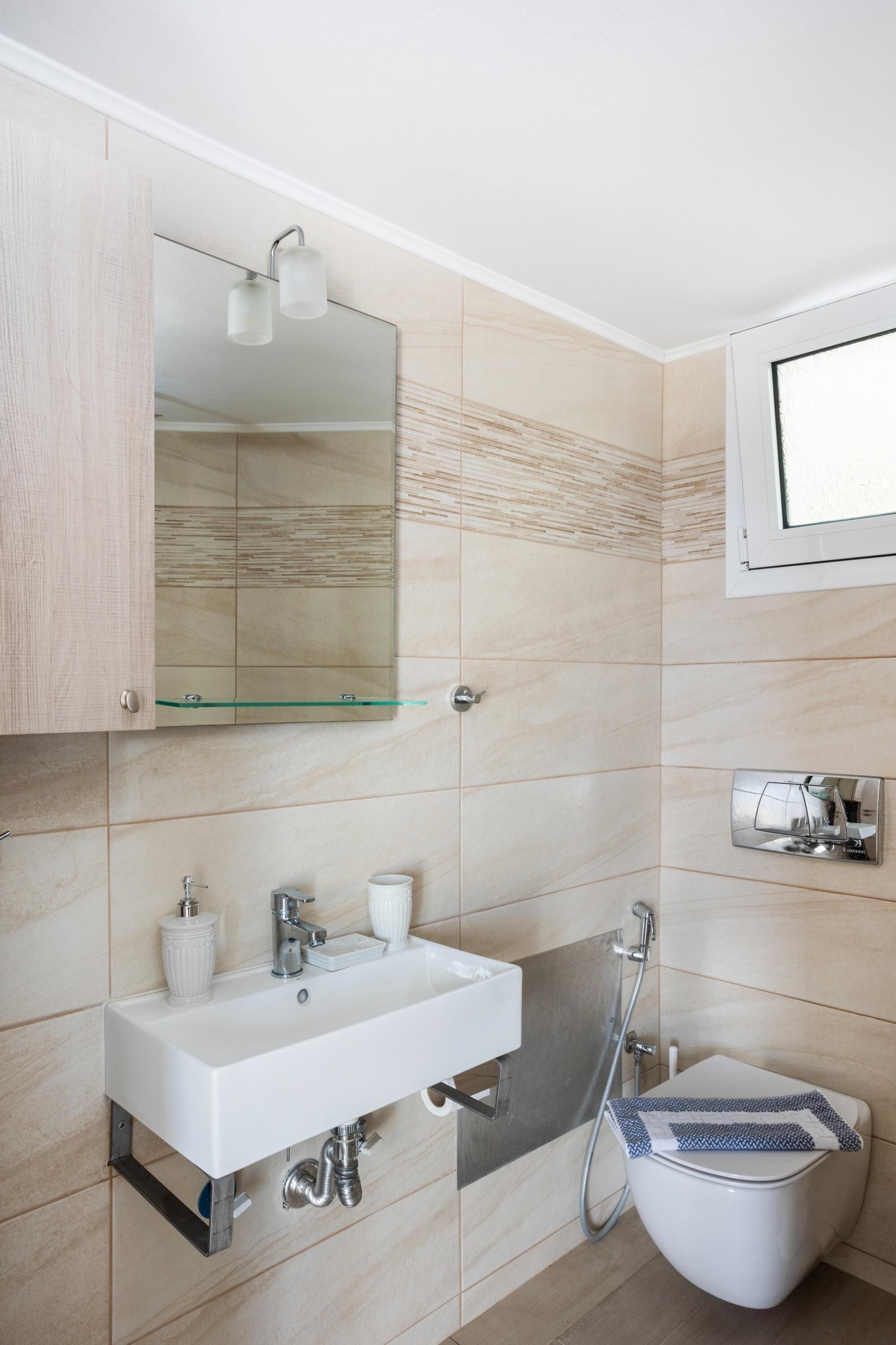 A modern bathroom with a white sink, mirror, and shower.