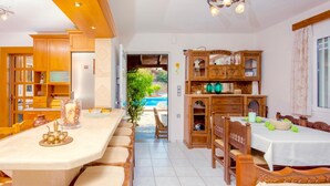 Uma sala de jantar espaçosa com móveis de madeira, uma ilha grande e vista para uma piscina.