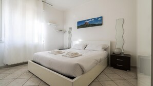 Une chambre moderne avec un lit, une table de chevet, un tableau et une sculpture murale originale.