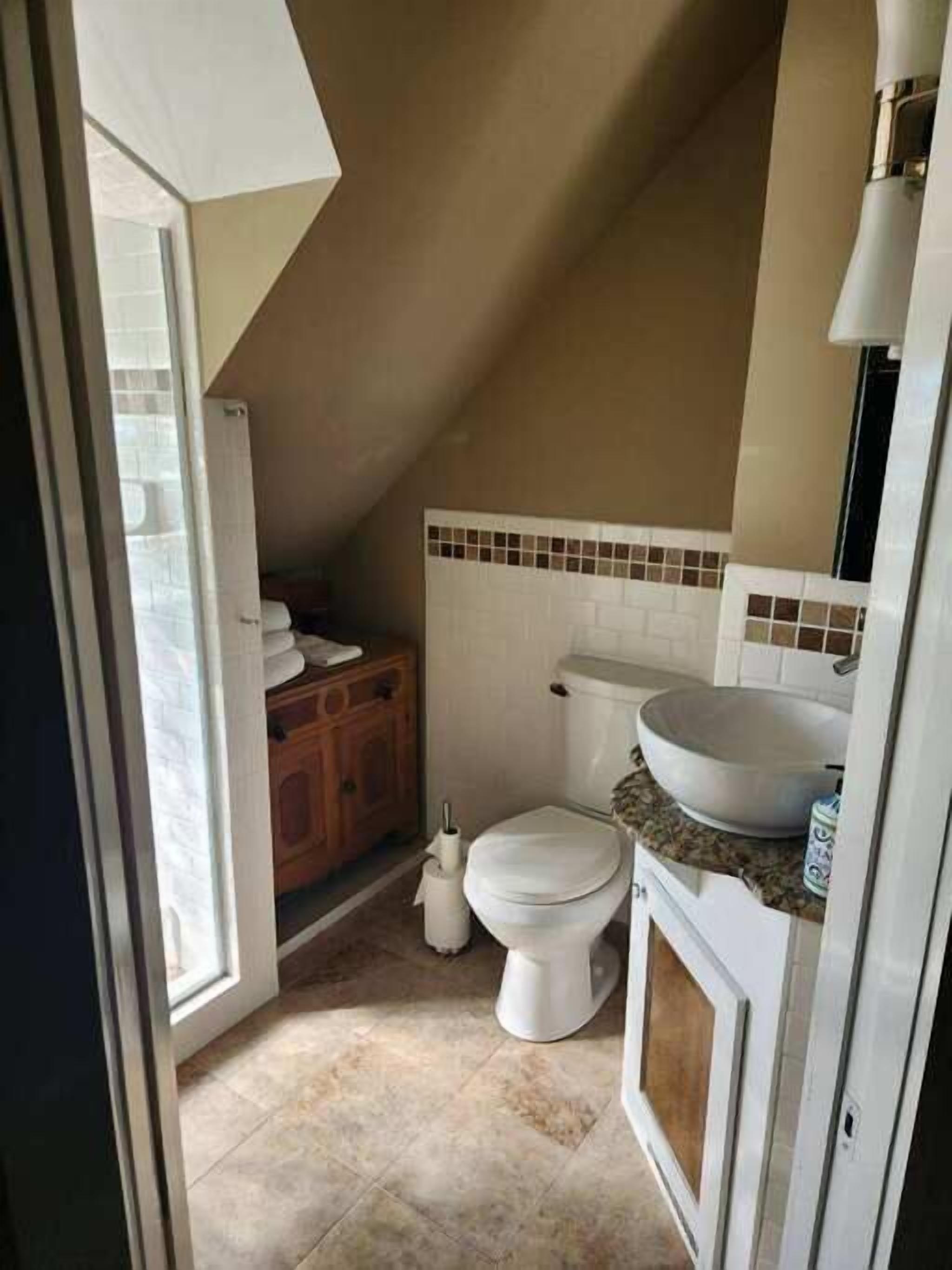 A small bathroom with a toilet, sink, and cabinet.