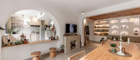 A modern kitchen with an island, wooden stools, and a TV.