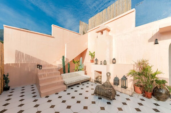 A sunlit courtyard with a staircase, potted plants, and a seating area. - Distant Mountain Guesthouse (Shenzhen)