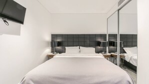 A modern hotel room with a large bed, a flat-screen TV mounted on the wall, and a large mirror reflecting the bed and a window. - lovely ap in  heart of chatswood (Chatswood)