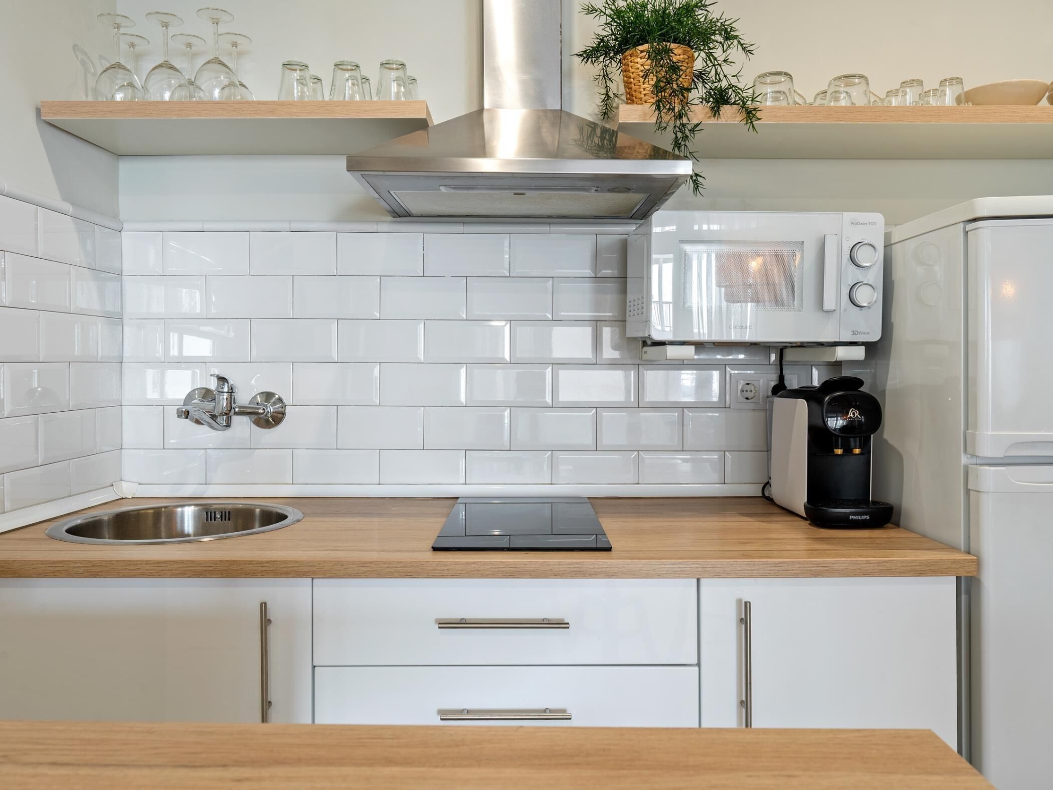 Una cocina moderna con azulejos blancos tipo metro, electrodomésticos de acero inoxidable y encimeras de madera.