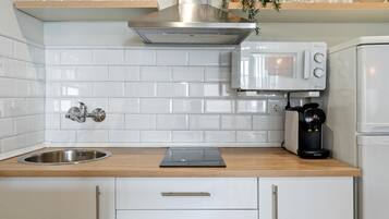 Una cocina moderna con azulejos blancos tipo metro, electrodomésticos de acero inoxidable y encimeras de madera.