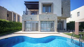 A modern two-story building with a swimming pool in front.