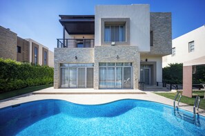 A modern two-story building with a swimming pool in front. - Villa With Private Pool In Beverly Hills (Sheikh Zayed City)