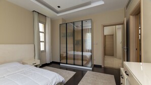 A modern bedroom with a large bed, a walk-in closet, and a separate bathroom.