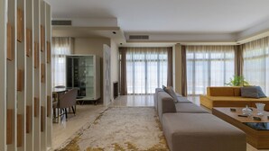 A modern living room with a sectional sofa, a glass coffee table, and a dining area with a table and chairs.