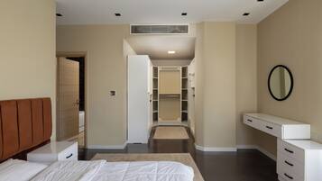 A bedroom with a bed, a bedside table, a dresser, a walk-in closet, and a mirror on the wall.