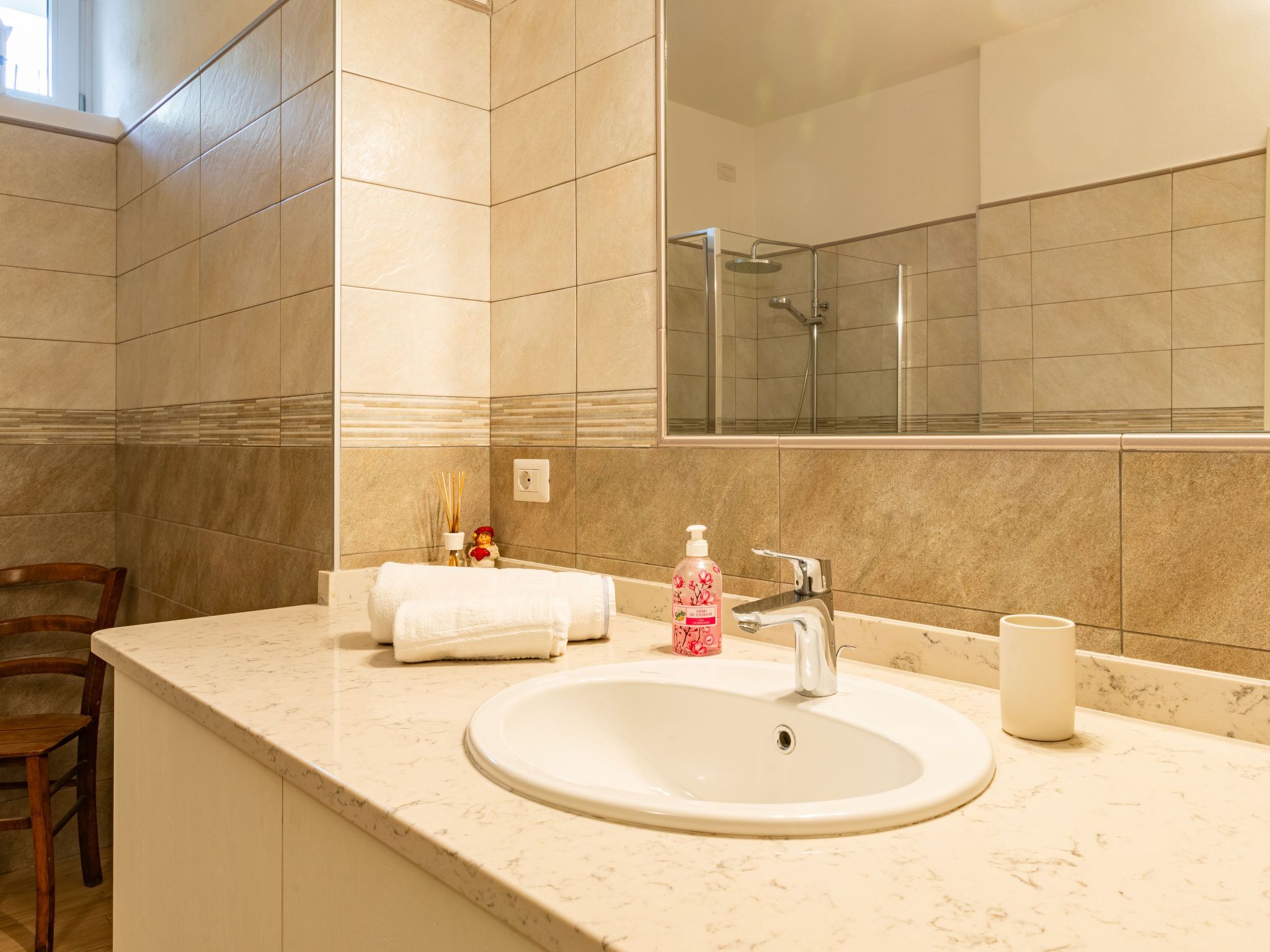 Een badkamer met een wastafel, spiegel en douche.