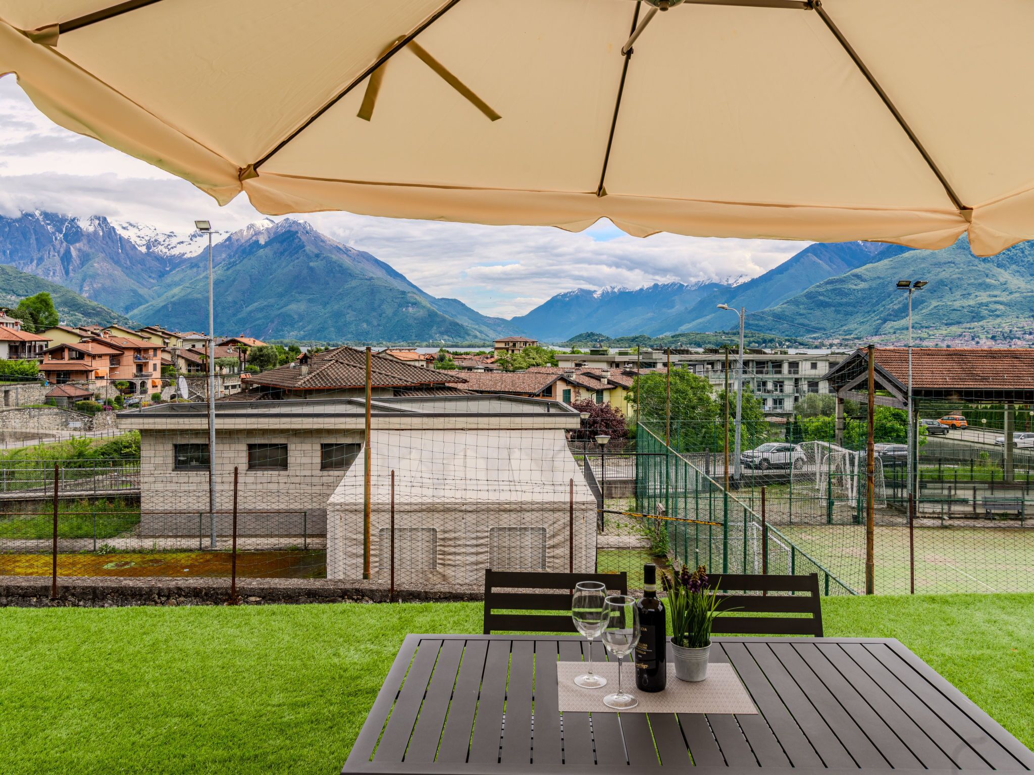 A terrace with a table and chairs, overlooking a mountainous landscape with buildings in the background.