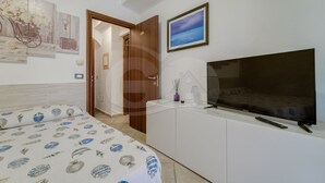 Une chambre à coucher comprenant un lit, une télévision, une armoire et une porte donnant sur une autre pièce.