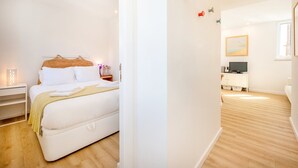 Une chambre à coucher moderne avec un lit, une table de chevet, une lampe et une vue sur le salon.