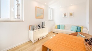 Un salon moderne avec un canapé blanc, une table basse en bois et un meuble blanc contenant des appareils électroniques.