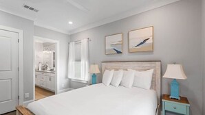 Une chambre à coucher avec un grand lit, deux tables de chevet avec des lampes, une tête de lit en bois et deux tableaux encadrés accrochés au mur.