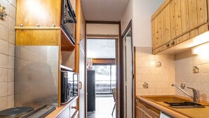 Une cuisine étroite avec des meubles en bois, un lave-vaisselle Bosch et une fenêtre.