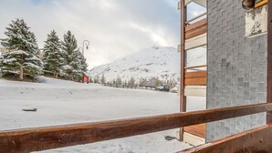 Un espace extérieur enneigé, avec une clôture en bois, un bâtiment doté d’un mur en briques et des arbres recouverts de neige.