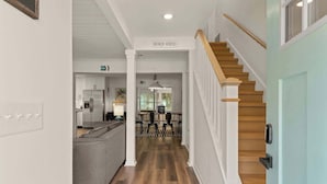 Un couloir menant à une cuisine et à un coin repas, avec un escalier.