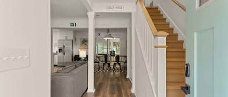 A hallway leading to a kitchen and a dining area with a staircase.