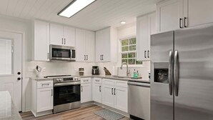 Une cuisine moderne avec des meubles blancs, des appareils en acier inoxydable et un tapis à motifs.