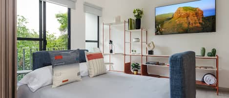 Un dormitorio moderno con una cama grande, un escritorio y un televisor.