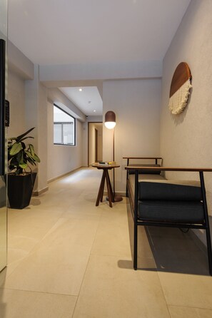 A modern hallway with a potted plant, a standing lamp, and a bench.