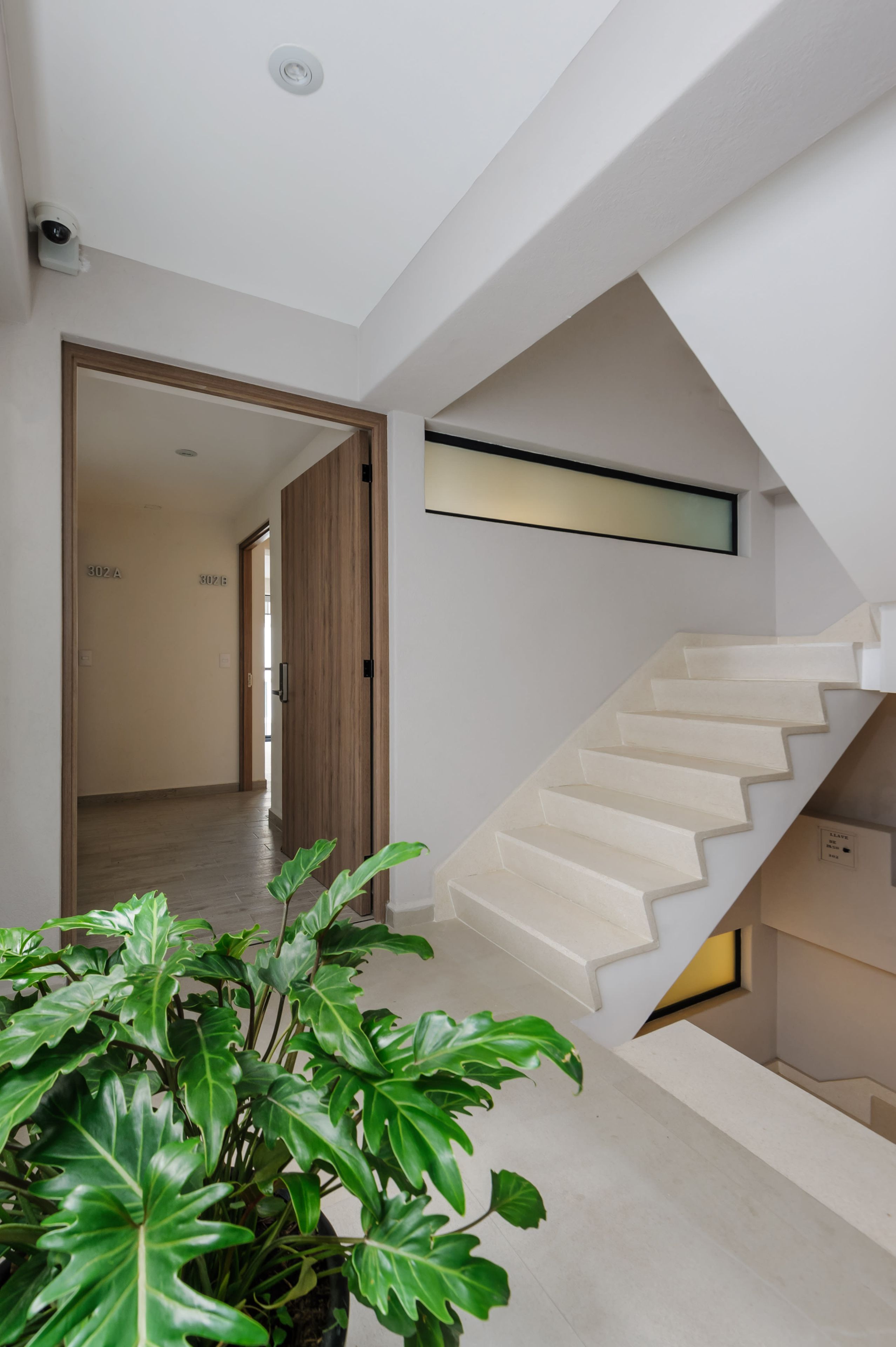 A modern staircase with a wooden door leading to a hallway.