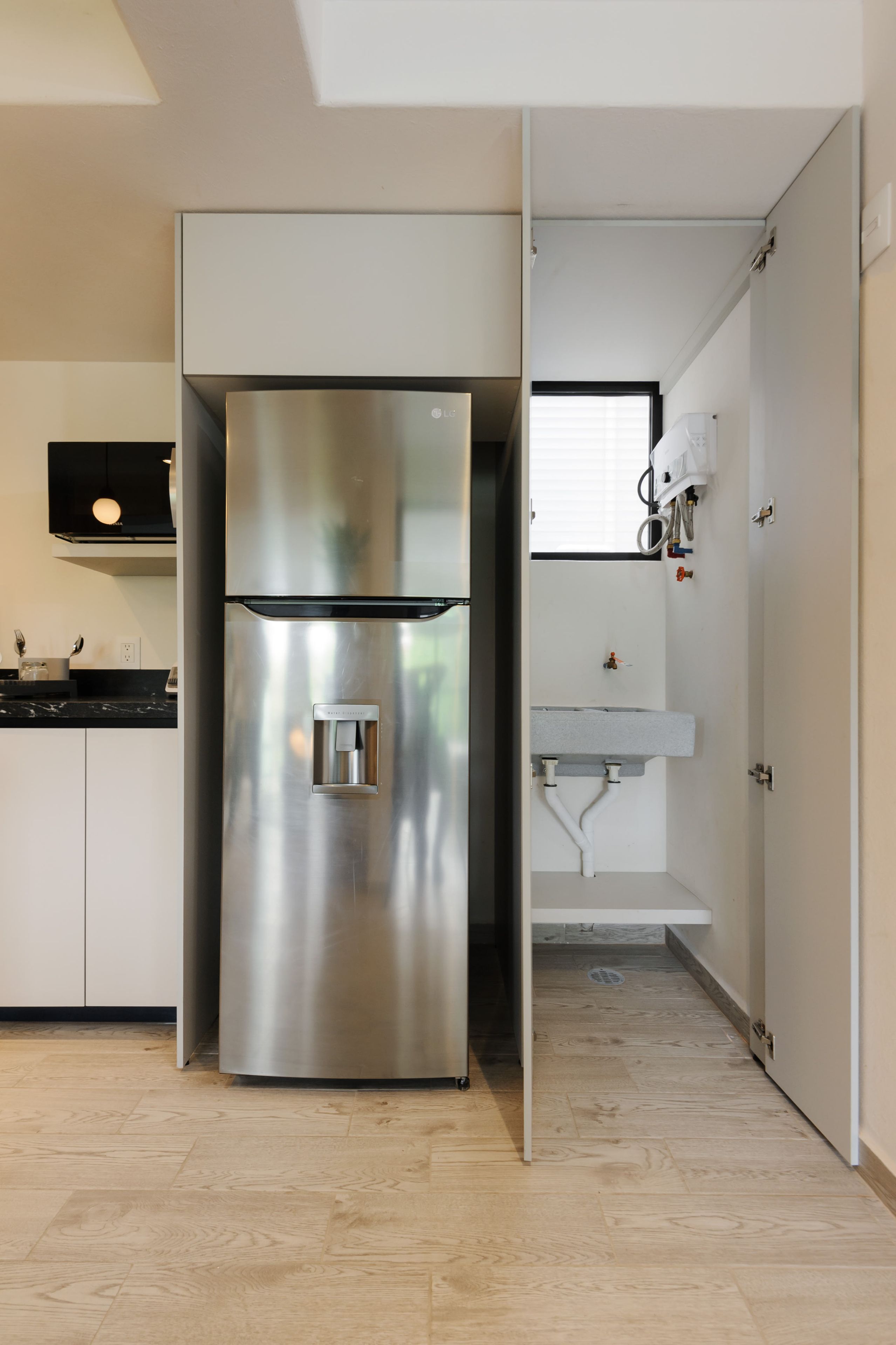 Eine moderne Küche mit einem Edelstahl-Kühlschrank, einer schwarzen Arbeitsplatte und einem weißen Spülbecken.