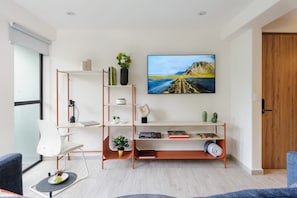 A modern living room with a white sofa, a coffee table with a fruit bowl, a bookshelf, and a large painting on the wall. - Choapan: Apartment with Great Location in Condesa (Ciudad de México)