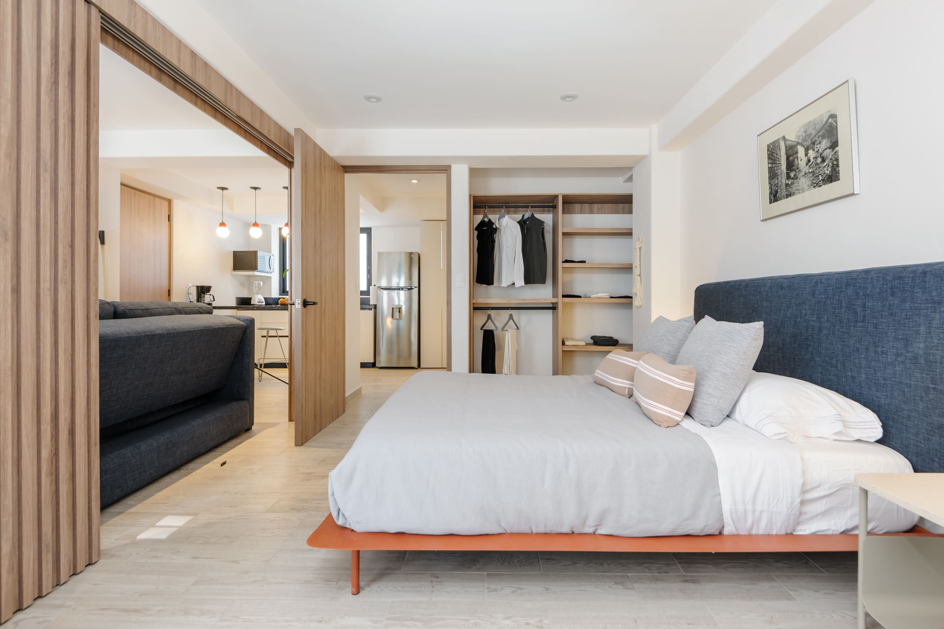 Una camera da letto moderna con un letto, un armadio, una zona salotto e un angolo cottura.