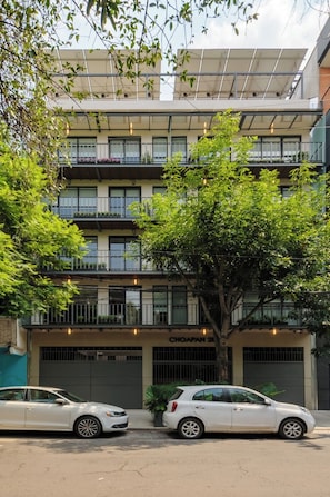 A multi-story building with balconies, a car parked in front, and a tree in the foreground. - Brand New Modern Apartment in Condesa (Ciudad de México)